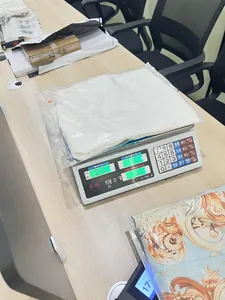 Vista dettagliata di un indumento bianco confezionato pesato su una bilancia digitale