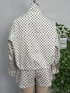 Back view of women's white and black polka dot jacket and shorts set with stand collar