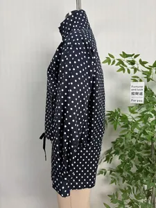 Side view of navy blue polka dot women's jacket with stand collar and long sleeves