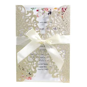 Elegant glittery gold laser-cut invitation card featuring a white satin ribbon bow detail