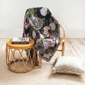 Coperta bohémien in tessuto con motivo floreale e frange su una sedia di vimini