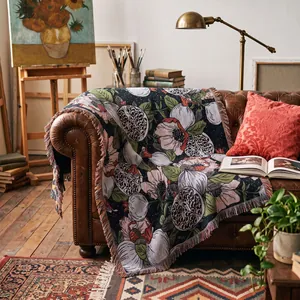 Coperta tessuta bohémien con motivo floreale di melograno su un divano di pelle.