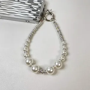 Detailed view of luxury phone charm featuring graduated white pearls and shimmering rhinestones.