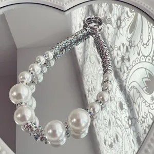 Detailed macro view of elegant white pearl phone charm with sparkling rhinestone spacers.