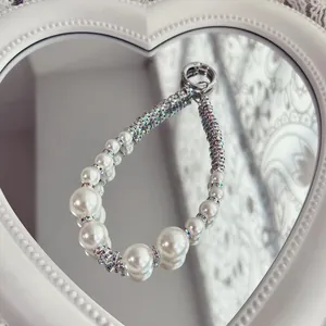 Close-up of elegant pearl phone strap with crystal-encrusted spacers on mirror