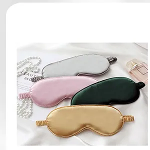 Close-up of four soft faux silk sleep eye masks on an elegant white fabric background