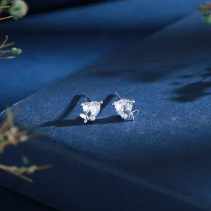 Vue macro de boucles d'oreilles puces papillon et cœur en argent sur un fond bleu texturé