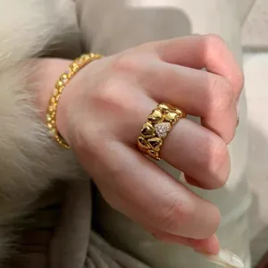 Primer plano de un anillo de doble corazón dorado con detalles de pavé de diamantes.