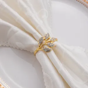Detailaufnahme eines goldenen Serviettenrings in Blattform mit funkelnden klaren Strasssteinen