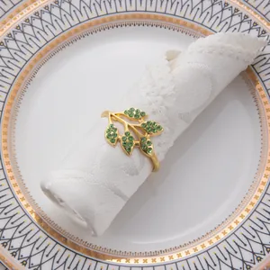 Detailansicht eines eleganten goldfarbenen Blattserviettenrings mit grünen Steinen.