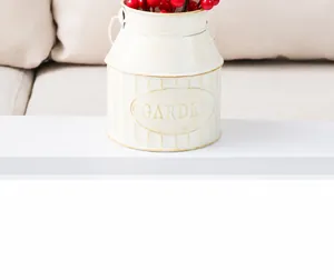 Close-up of vintage white metal milk jug flower bucket with embossed Garden text