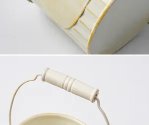 Detailed view showing the sturdy metal handle and welding craftsmanship on a vintage iron bucket