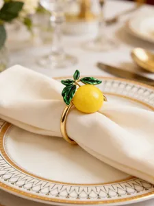 Gros plan d'un rond de serviette citron jaune sur une serviette blanche, table dressée.