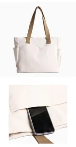 Detail of cream canvas tote bag showing exterior pocket for smartphone storage.