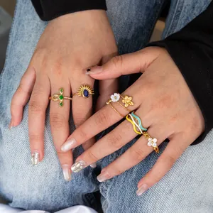 Detail of 18K gold plated stainless steel rings with zircon and enamel on hands