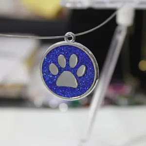 Close-up view of a 30mm blue glitter dog paw print pendant for pet identification tags