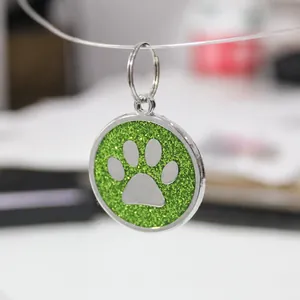 Close-up of a 30mm green glitter dog paw print pet ID tag made of zinc alloy