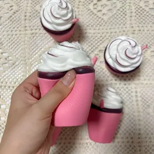 Détail d'un gobelet de glace squishy rose en PU pressé à la hand sur une nappe en dentelle