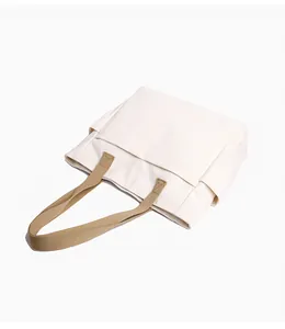 Detailed view of cream canvas tote bag with contrasting khaki straps on white background
