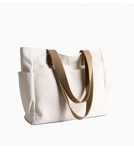 Detailed macro view of a large capacity canvas tote bag with side pockets and brown straps
