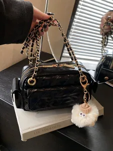 Elegante bolso de hombro acolchado negro con cadena dorada y un suave colgante blanco