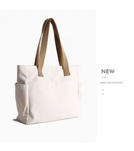Close-up detail of a minimalist white canvas tote bag featuring durable tan shoulder straps