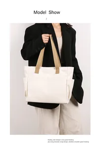 Minimalist white canvas tote bag with khaki straps worn by model
