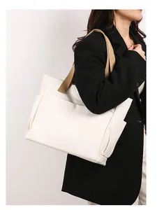 Detailed shot of a large white canvas tote bag worn by a woman for daily commute