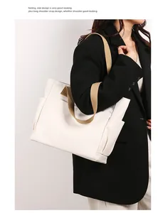 Close-up detail of a minimalist white canvas tote bag with khaki straps on a model