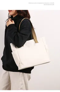 Large off-white canvas tote bag worn on shoulder by model