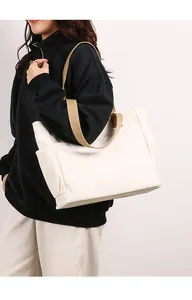 Model carrying a large white canvas tote bag with comfortable khaki shoulder straps