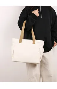 Minimalist large capacity white canvas tote bag with khaki straps shown on a lifestyle model