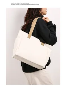 Detailed view of a minimalist cream canvas tote bag with durable khaki shoulder straps