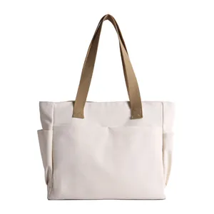Minimalist white canvas tote bag with brown handles and multi-pocket design