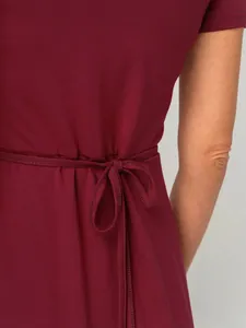 Detail of burgundy maternity dress showing waist tie and soft fabric texture