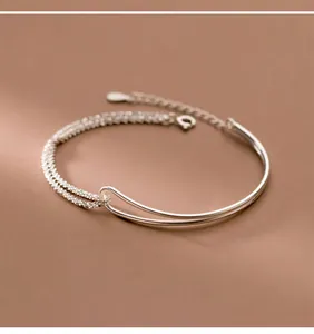 Minimalist silver double-layer bracelet with curved tube and stardust texture chain.