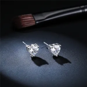 Close-up of sparkling heart-shaped moissanite stud earrings with a shiny silver finish.