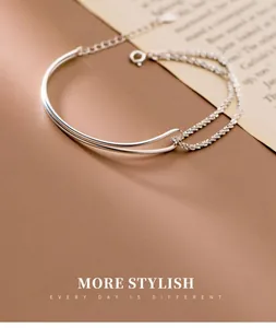 Close-up of asymmetrical silver bracelet featuring a sleek curved bar and twisted chain.