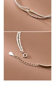 Detailed view of a silver double-layer bracelet with curved tube and sparkling chain elements