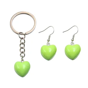 Detail view of lime green heart-shaped resin pendant keychain and matching hook earrings set