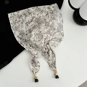 Detailansicht eines geblümten Satinschals mit eleganten Marmorperlen-Akzenten an den Ecken.