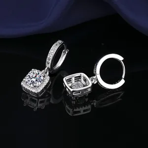 Close-up detail of silver princess-cut halo earrings with shiny cubic zirconia stones.