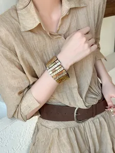 Gros plan d'un large bracelet en acrylique marbré aux motifs rétro sur le poignet d'un mannequin