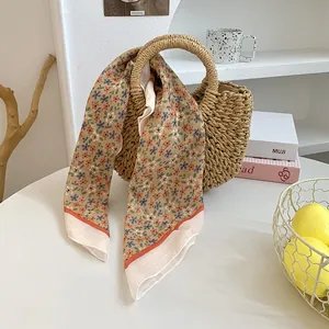 Eleganter Seidenschal mit Blumenmuster auf einer Strohtasche für den Beruf.