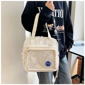 Detail view of cream white tote bag with transparent mesh pocket and blue fashion badge