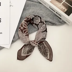 Nahaufnahme eines braun gemusterten Satin-Halstuchs, das zu einer stilvollen Schleife gebunden ist