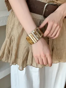 Détail d'un bracelet vintage en acrylique marbré avec des accents dorés sur modèle
