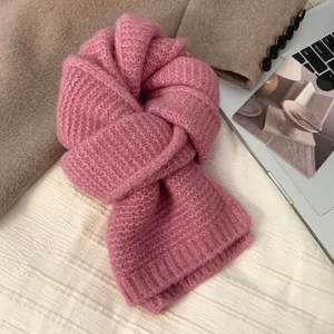 Detailansicht eines rosa Strickschals mit grober Rippenstruktur auf einem flachen Hintergrund