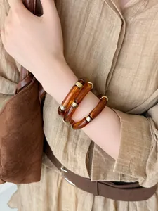 Gros plan de bracelets empilés en acrylique ambré vintage avec des accents dorés