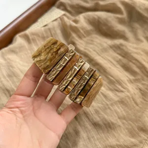 Détail d'un bracelet vintage en acrylique ambré avec des maillons dorés texturés